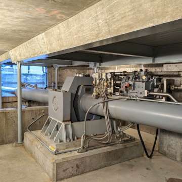 Large bore miter gate hydraulic cylinder with gimbal and onboard valve assembly installed in a machinery room