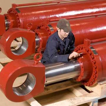 Technician inspecting large bore moonpool hydraulic cylinders after final assembly